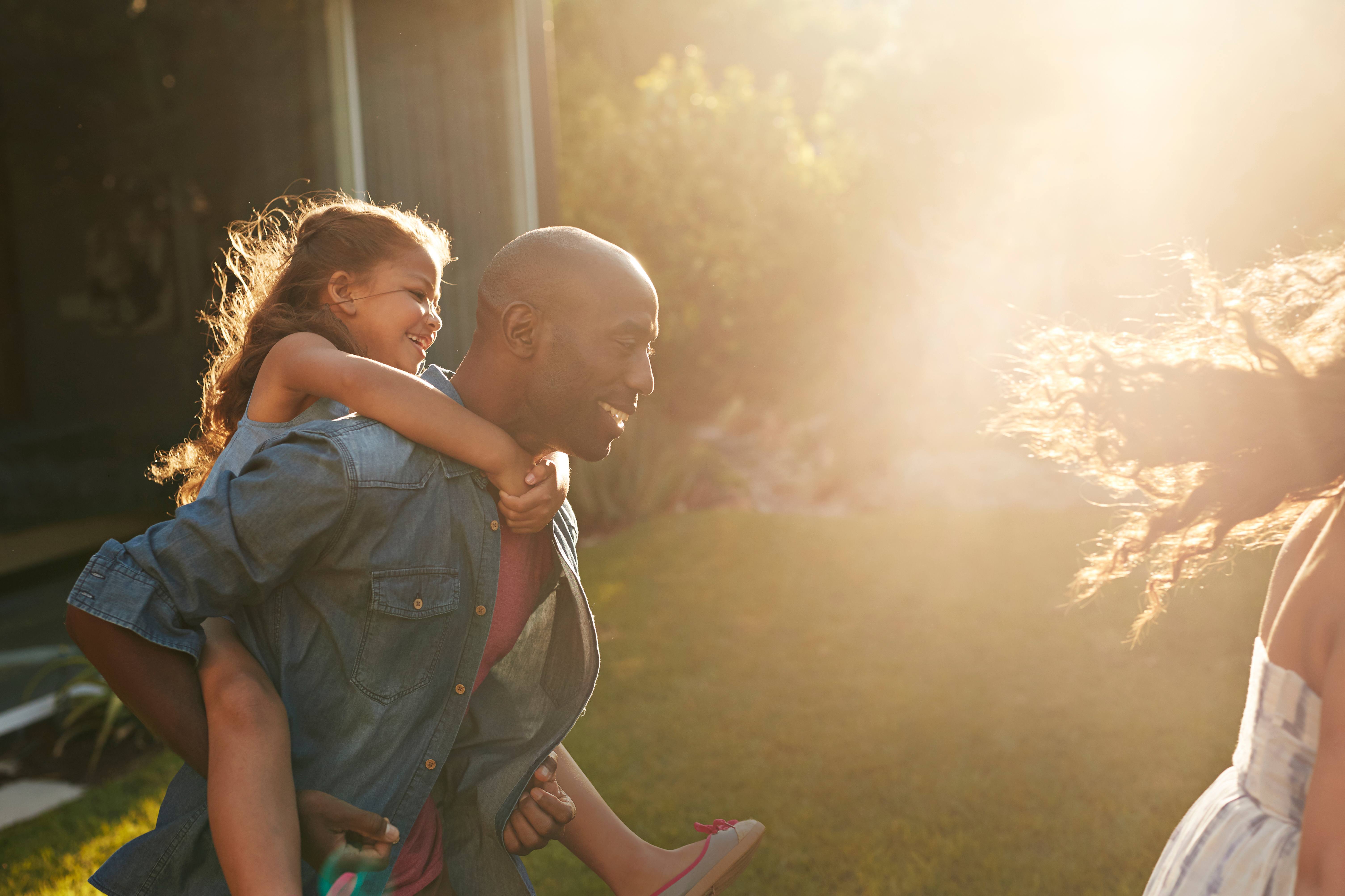 man carrying young girl on his back